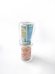 The image shows several stacks of rolled banknotes wrapped tightly in transparent plastic. Each stack consists of a blue banknote on top and a pink banknote beneath it