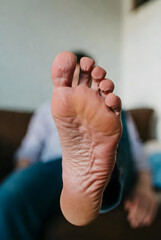 Close-Up of Bare Foot Sole in Focus with Person Relaxing in Background