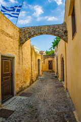 Narrow cobblestone alley with yellow stone walls and old doors in the Rhodes Old town, Greece