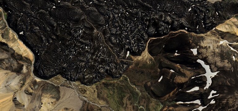 High-Contrast Satellite View of Textured Black Lava Flow and Snow-Covered Mountains - Powered by Adobe