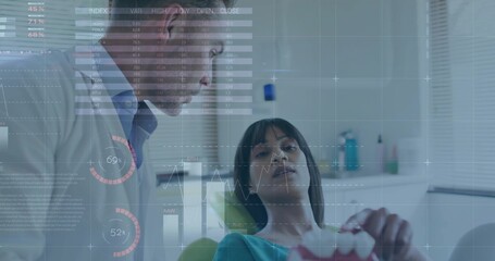 Explaining dentist in white lab coat leaning over patient in clinic chair, holding pink model HUD