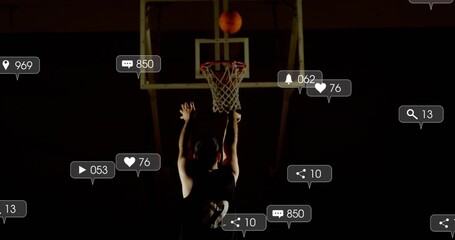 Jumping backlit male athlete reaching toward hoop at gym, with basketball, jersey, social alerts