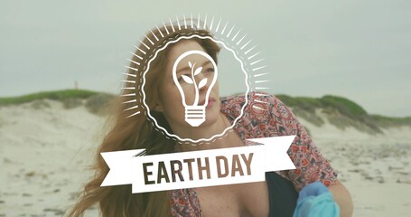 Posing woman wearing patterned coverup dark swimsuit on beach holding blue glove Earth Day overlay