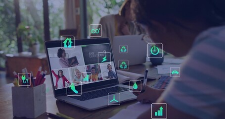 Writing child in striped shirt holding pen referencing laptop call at wood table, with energy icons