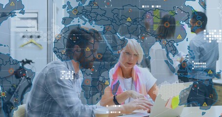 Collaborating man in checked shirt, woman in pink scarf pointing at laptop in office, data overlays