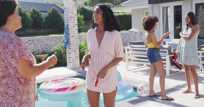 Laughing woman wearing striped dress holding red object on deck by plunge pool, with lollipop float - Powered by Adobe