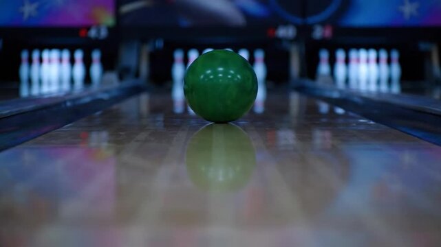 A close-up shot of a green bowling ball on the lane, with the pins blurred in the background
