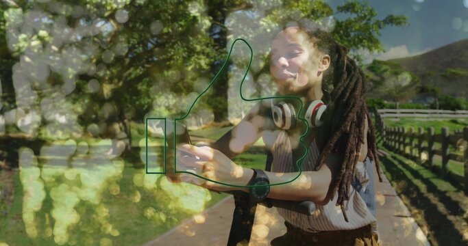 Holding smartphone, woman leaning on scooter, wearing headphones, striped top in park, thumbs-up