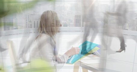 Holding woman in blazer flipping teal folders at office desk, with blurred pedestrians, skyline