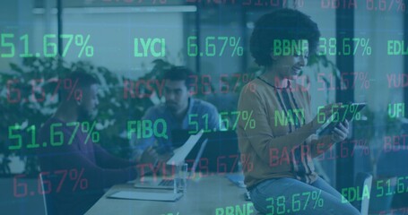 Interacting curly woman in mustard top and jeans using tablet at office, ticker overlay, copy space