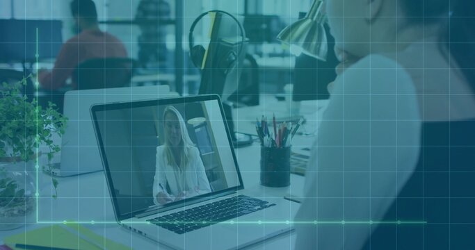 Viewing laptop showing seated woman in light colored blouse in open-plan office, with headphones
