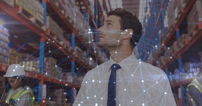 Inspecting man in white shirt dark tie checking racks and boxes in warehouse with mesh overlay