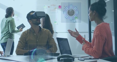 Exploring man wearing VR headset, button shirt navigating AR UI at meeting table with laptops