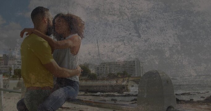 Sitting romantic couple embracing on seaside metal railing in yellow shirt and jeans, copy space - Powered by Adobe