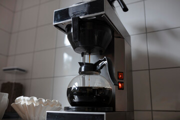 Intimate view of coffee maker brewing mechanism with fresh coffee dripping into glass carafe