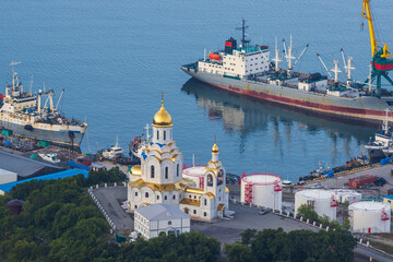 Top view of a beautiful church on the coast of the bay. The ships are moored to the piers of the port. Naval Cathedral, City of Petropavlovsk-Kamchatsky, Kamchatka Krai, Far East of Russia.
