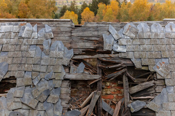 Heavily damaged roof section showing broken slate tiles and structural collapse © Victor