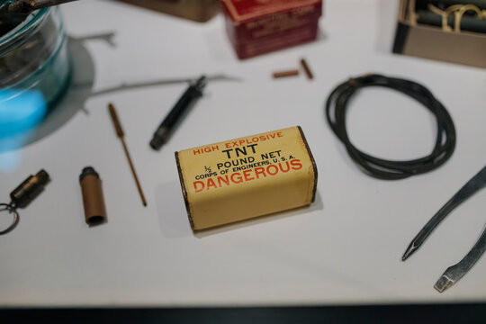 Vintage military demolition equipment including marked TNT box and various tools laid out on surface