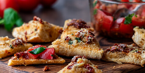 A close up of baguette triangles with a bowl of bruschetta in behind.