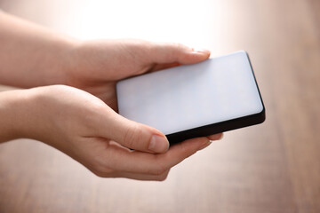 Woman with LED lamp on wooden background, closeup