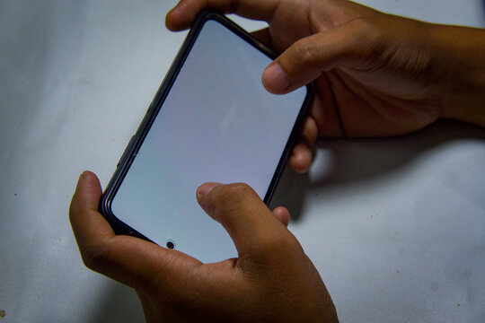 A hand holding a smartphone landscape mode isolated on white background 