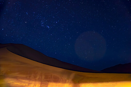 Star-trail of blue night sky with milky way on a dune, stars field and galaxies, from dunes of Empty quarter desert or Rub' al-Khali desert on Jannuary in Oman.