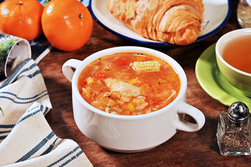 Italian tomato and chicken soup in a white bowl on a wooden background