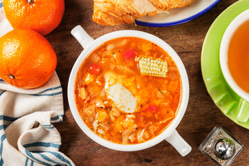 Italian tomato and chicken soup in a white bowl on a wooden background