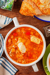 Italian tomato and chicken soup in a white bowl on a wooden background