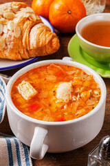 Italian tomato and chicken soup in a white bowl on a wooden background