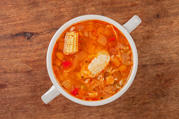 Italian tomato and chicken soup in a white bowl on a wooden background
