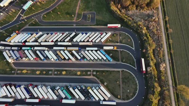 aerial view extensive trailer yard panorama with colorful rows of parked trailers, massive capacity and backlog impression, distribution hub scale, highway access and storage lanes