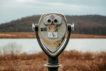 Binoculars in a park looking out onto a lake. 