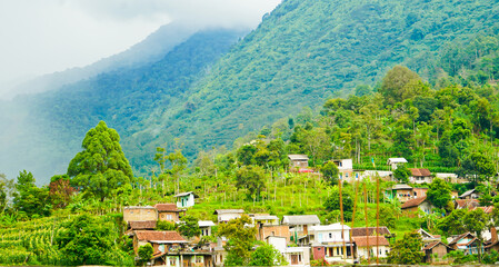 beautiful view of a village at the foot of a hill covered in mist