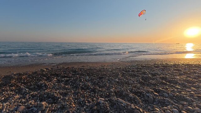 parachute behind the boat. Sunset rocky beach. High quality 4k footage