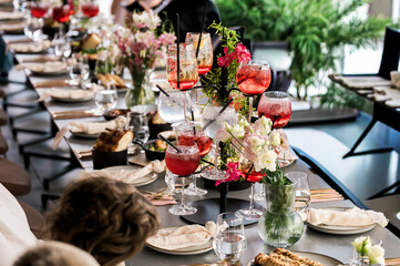 Elegant banquet table set with vibrant cocktails, fresh floral arrangements, gourmet dishes, and refined tableware, creating a luxurious celebration atmosphere perfect for events, weddings, or upscale