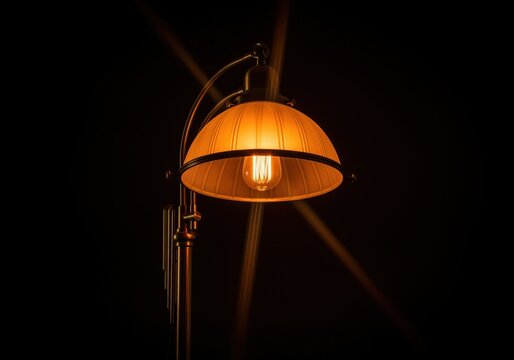 Dramatic low key photograph of a vintage brass floor lamp with a glowing edison bulb