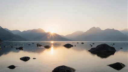 Obraz premium Serene Sunrise Over a Rocky Lake with Misty Mountains.