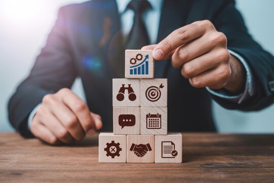 Businessman stacking wooden blocks with business icons