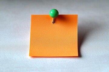 Empty orange square sticky note pinned with a green pushpin on a textured white surface, evoking neatness and quiet focus