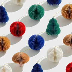 Colorful Paper Christmas Ornaments as round balls and Christmas trees, hanging eco-friendly New Year decorations. Minimal aesthetic holidays repeat pattern, top view backdrop of winter baubles.