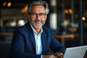mature professional man in navy suit working on a laptop in a modern office with warm ambient lighting, calm confident and focused posture
