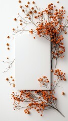 A blank white card is framed by delicate dried orange flowers and small golden beads, creating a festive and elegant arrangement on a white surface.