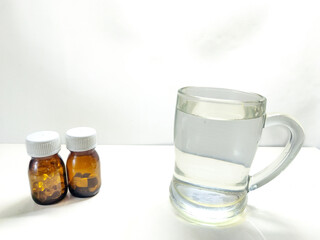 Taking a daily dose of medicine with a glass of water, representing healthcare, treatment, and pharmaceutical concepts on a white background