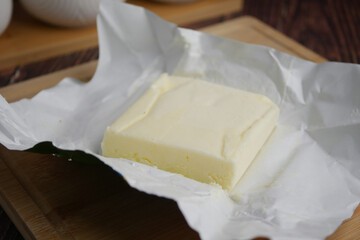 Fresh butter wrapped in paper on a wooden cutting board