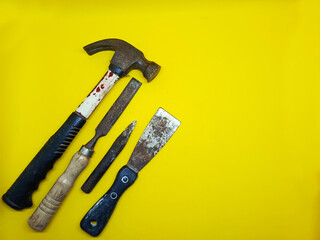 Collection of carpentry tools including a hammer, chisel, and scraper on a yellow background