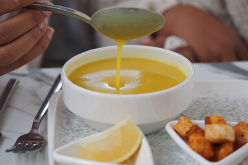 Warm yellow soup served with lemon and croutons