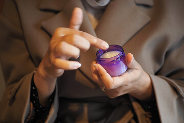 Applying cream from a small jar with care indoors