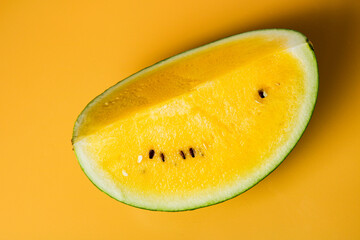 Sliced yellow watermelon with bright, juicy interior displayed against a clean yellow surface. Perfect for illustrating exotic produce, freshness, and natural nutrition.