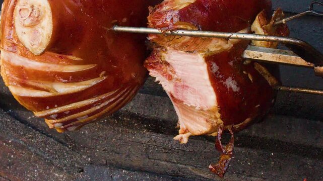 Traditional Pork Knuckle Roasting on Spit Over Wood Fire